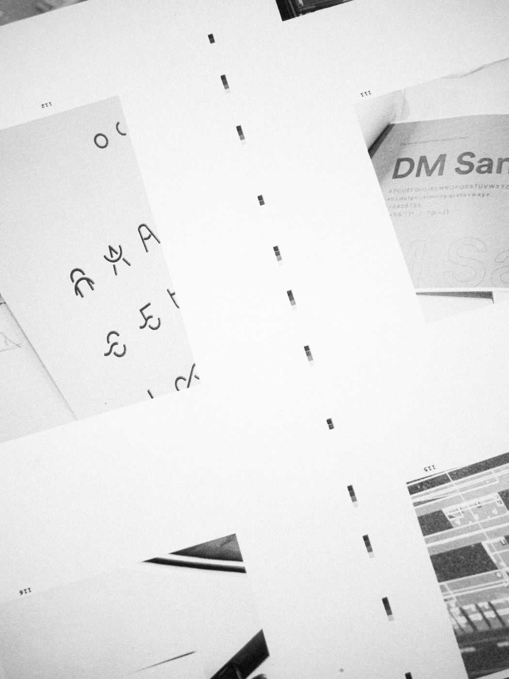 Feuilles d'esquisses et de recherches typographiques éparpillées sur une table.